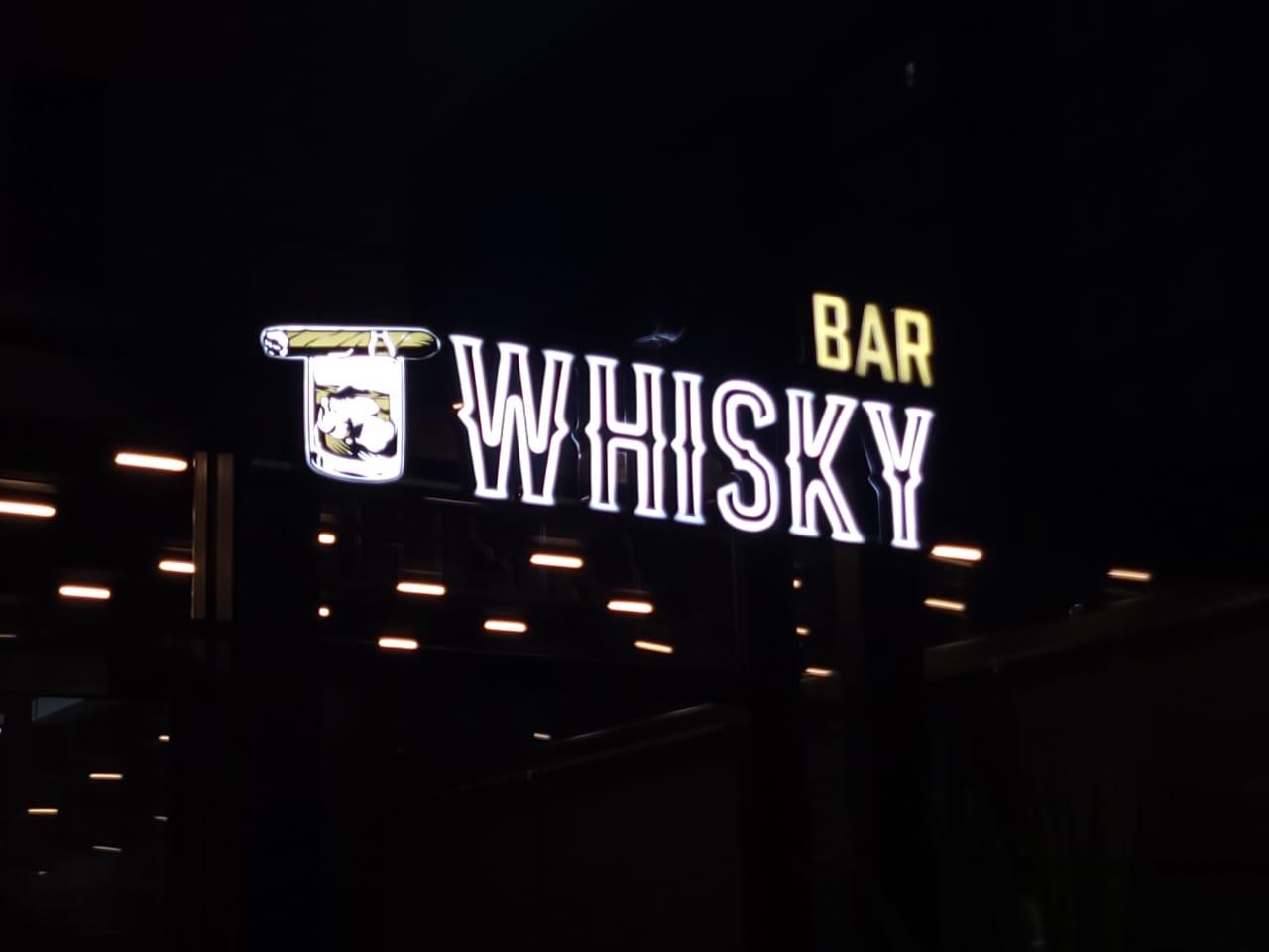 Shkronja WHISKY me kontur neon të bardhë, BAR në të verdhë dhe ikona e gotës me puro, natën