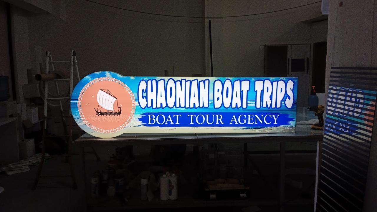Lightbox Chaonian Boat Trips me trierë antike dhe det blu, i ndezur mbi tavolinën e studios