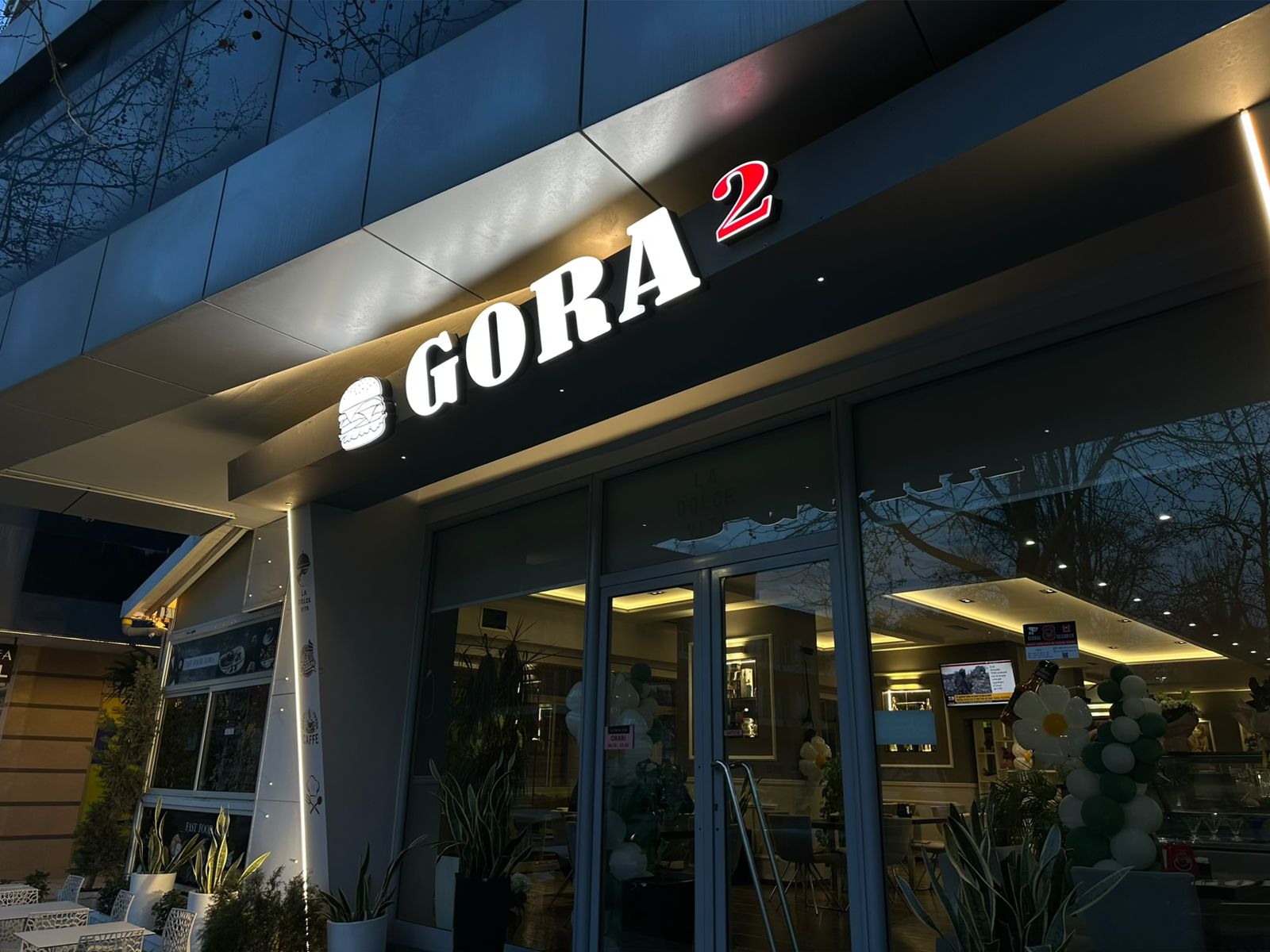 Shkronja 3D të ndriçuara GORA 2 mbi fasadën e lokalit në muzg